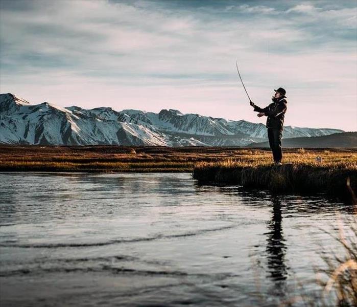 man fishing with beautiful mountains in the background