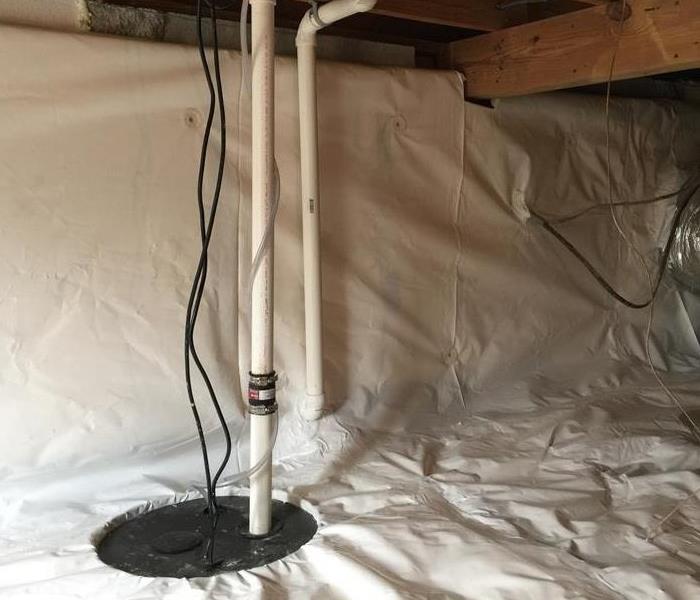 a cleaned and encapsulated crawlspace that has a visible sump pump with a few wires hanging from the ceiling
